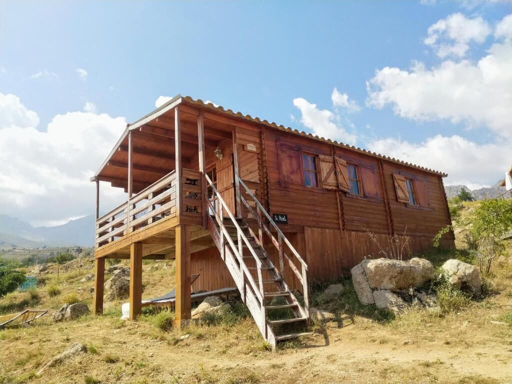 Une cabane en bois dotée d’un balcon et d’un escalier menant à une terrasse.
