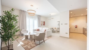 A modern living room with a sofa, coffee table, and chairs, a dining area with a table and chairs, and a kitchen area with cabinets and a countertop. - Bloomfields 2BR plus Maid in Yas Golf  (Abu Dhabi)