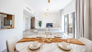 A modern dining area with a marble table, white plates, and gold candle holders. - Bloomfields 2BR plus Maid in Yas Golf  (Abu Dhabi)