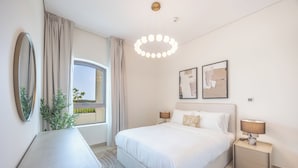 A modern hotel room with a large bed, bedside lamps, a mirror, and artwork on the wall. - Bloomfields 2BR plus Maid in Yas Golf  (Abu Dhabi)