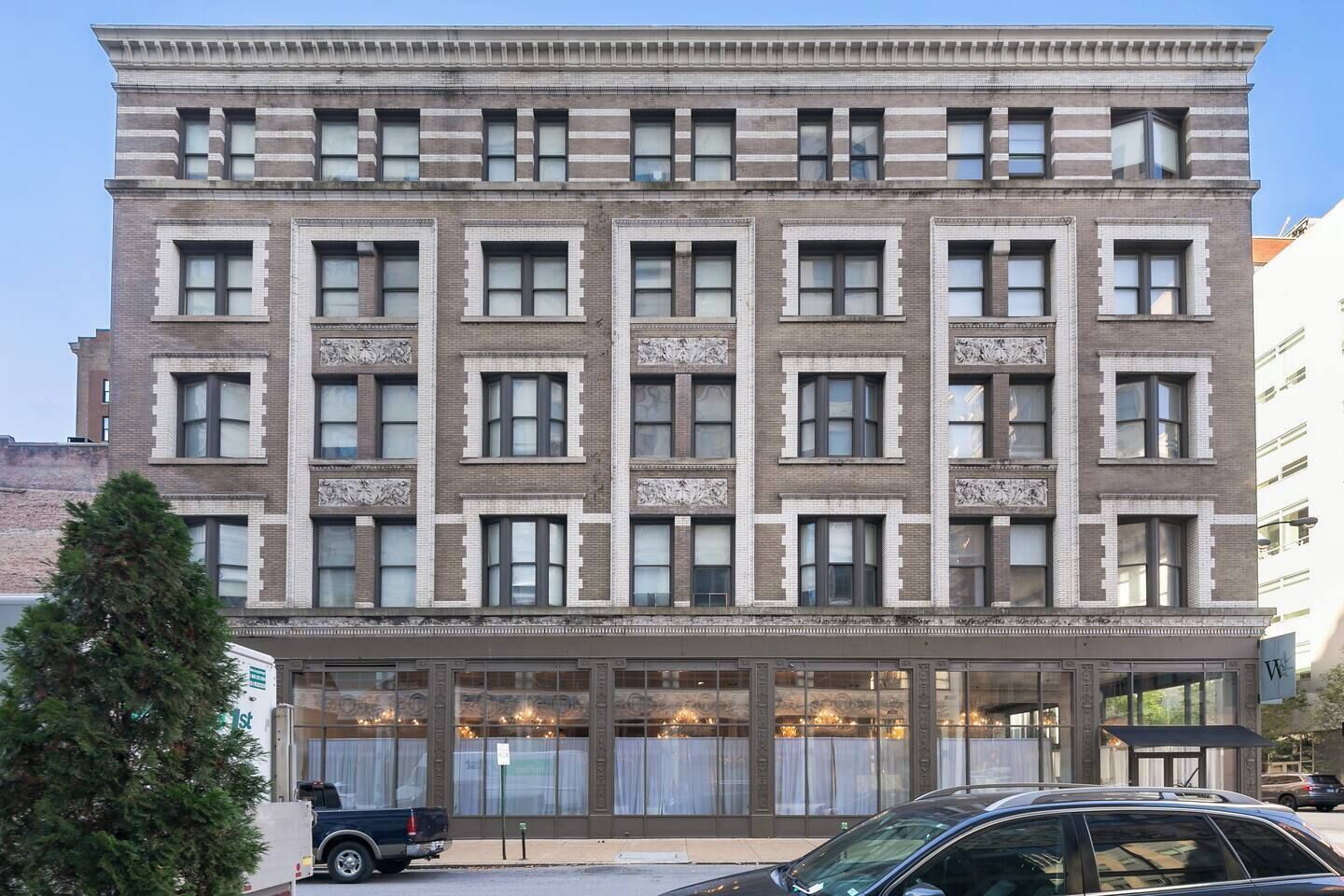 A multi-story building with a symmetrical facade, large windows, and a ground-level entrance with a glass facade.
