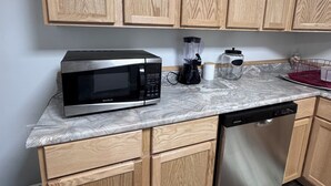 A kitchen with wooden cabinets, a microwave, a blender, and a dishwasher.