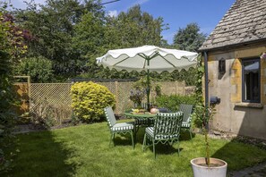 Eine Terrasse mit Tisch, Stühlen, einem Blumentopf und einem weißen Sonnenschirm.