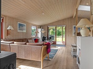 A spacious living room with a large L-shaped sofa, a dining table, and a kitchen area with a white refrigerator. - "Christiern" - 600m from the sea by Interhome (Bindslev)