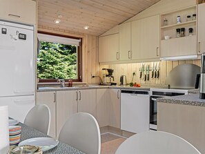 Eine moderne Küche mit Holzausstattung, einem Backofen und einem Fenster mit Blick auf Grünflächen.