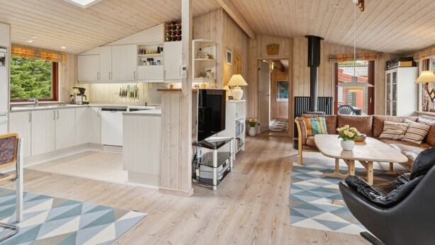 Ein modernes Interieur mit Küche, Essbereich und Wohnbereich, mit Holzböden und einem Oberlicht.
