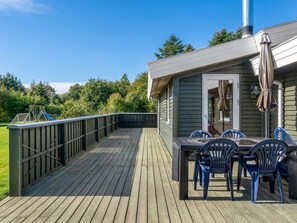 Une terrasse en bois avec une table et des chaises, un patio couvert et une vue sur une aire de jeux.