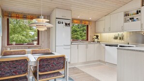 Eine moderne Küche mit Essbereich, Holzboden und großen Fenstern.