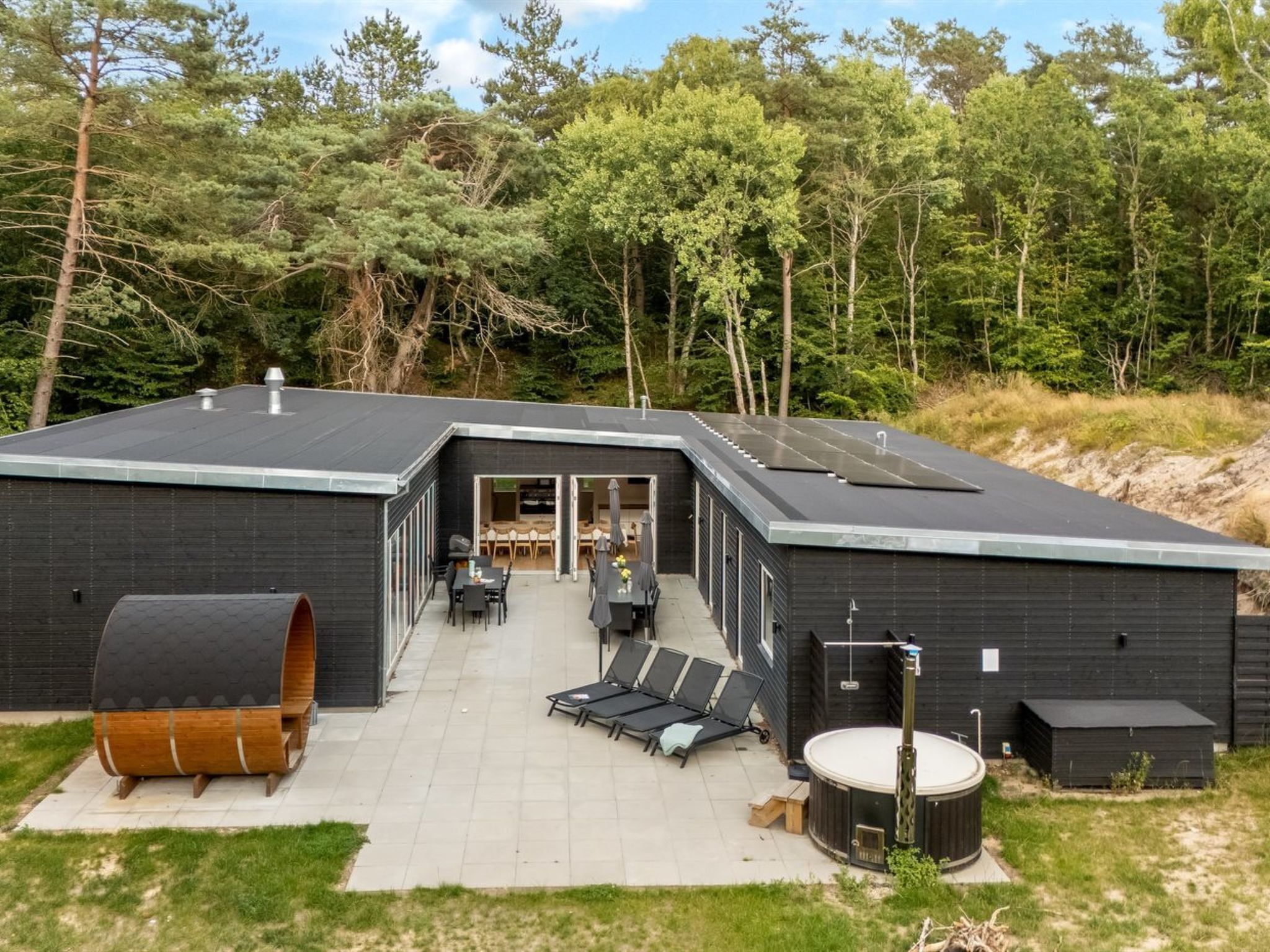 Un edificio moderno con patio, mobiliario exterior y una bañera de hidromasaje.