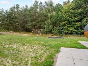 A backyard with a swing set, a trampoline, and a paved area. - "Adisl" - 800m from the sea by Interhome (Hadsund)