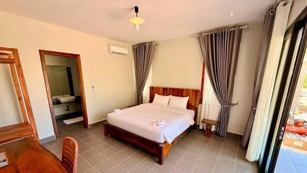 Habitació d'hotel amb llit, escriptori i cadira. Hi ha un bany amb mirall i rentapeus.
