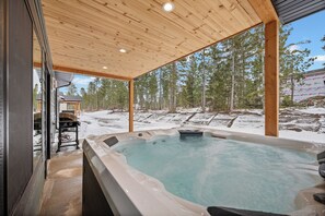 Un jacuzzi con techo de madera y vista a un paisaje nevado.