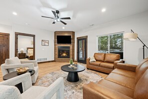 Una sala de estar moderna con chimenea, sofá de cuero y ventilador de techo.