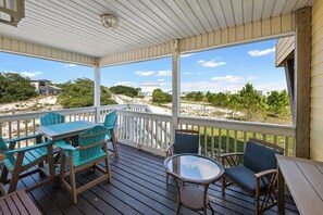 Eine überdachte Terrasse im Freien mit Holzmöbeln und Blick auf den Strand.