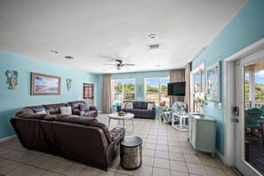 Ein Wohnzimmer mit braunem Sofa, rundem Couchtisch und Deckenventilator.