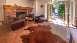 Uma sala de estar com lareira de tijolos, sofás de couro, uma mesa de centro e um tapete de couro.