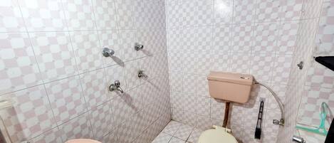 Un baño con lavamanos, inodoro y ducha de color rosa.