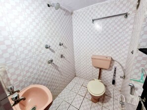 Un baño con lavamanos, inodoro y ducha de color rosa.