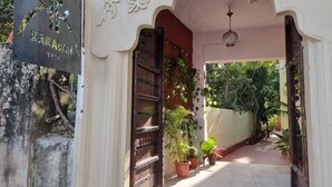 A traditional entrance with a sign, a wooden gate, and potted plants. - Karavan Kafe and Stay (Pushkar)