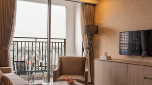 A modern hotel room with a balcony, a sofa, a coffee table, and a TV. - Maison de Gu Tresor Residence (Ho Chi Minh City)