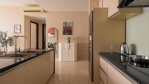 A modern kitchen with a black countertop, stainless steel appliances, a white refrigerator, and a potted plant on the cabinet. - Maison de Gu Tresor Residence (Ho Chi Minh City)