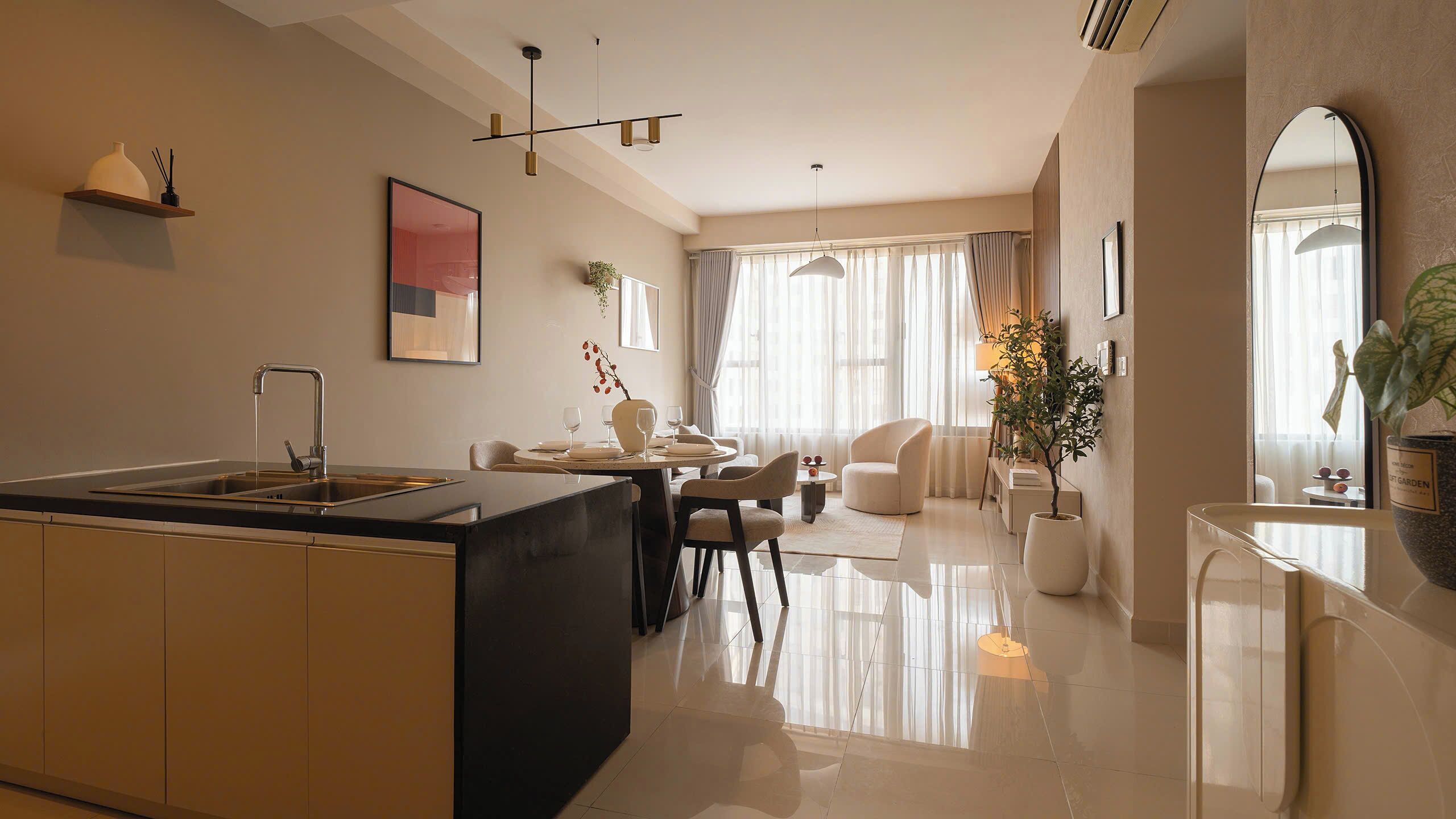 Una cocina moderna con una isla central, comedor con sillas y mesa, y sala de estar con sofá y planta.