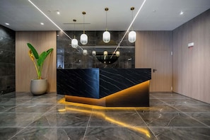 A reception desk with a marble top, a potted plant, and pendant lighting. - w Modern 1BR w Balcony View in San Francisco (Panama City)