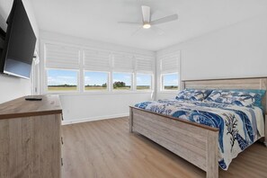 A bedroom with a bed, a desk, a ceiling fan, and large windows. - Brand NEW Boaters Dream in Slaughter Beach (Milford)