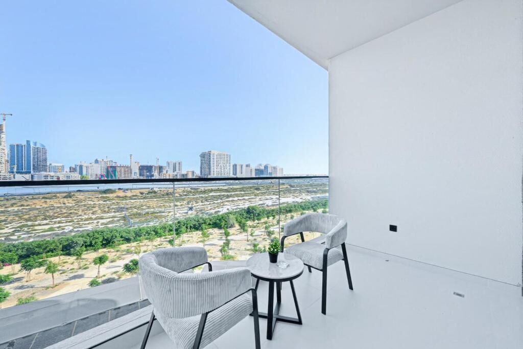 Varanda com duas cadeiras e uma mesa pequena, com vista para o horizonte da cidade e um rio.
