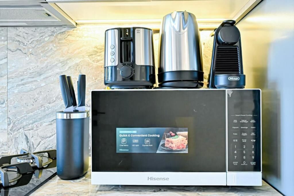 A Hisense microwave oven with a digital display and a coffee maker on top.