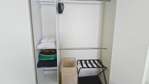 Un armario con una percha, repisas con ropa doblada y un contenedor de almacenamiento.