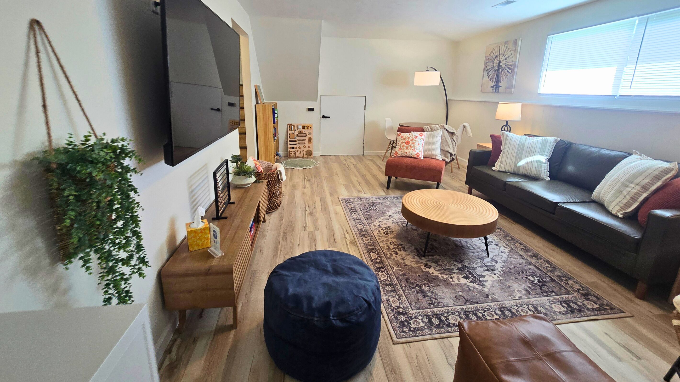 A living room with a TV, sofa, ottoman, and a rug.