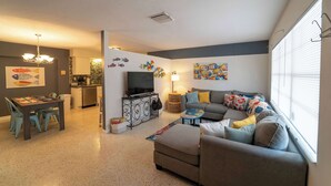 Sala de estar con sofá, televisor, mesa de comedor y sillas.