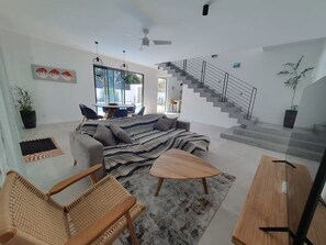 Ein modernes Wohnzimmer mit einer Couch, Sesseln, einem Couchtisch und einer Treppe.