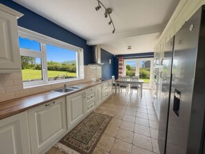 A kitchen with white cabinets, a stainless steel refrigerator, and a view of the outdoors.