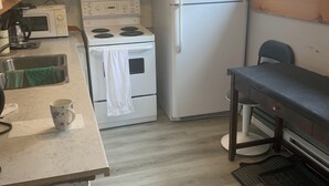 Een compacte keuken met witte apparaten, een koffiezetapparaat en een raam.