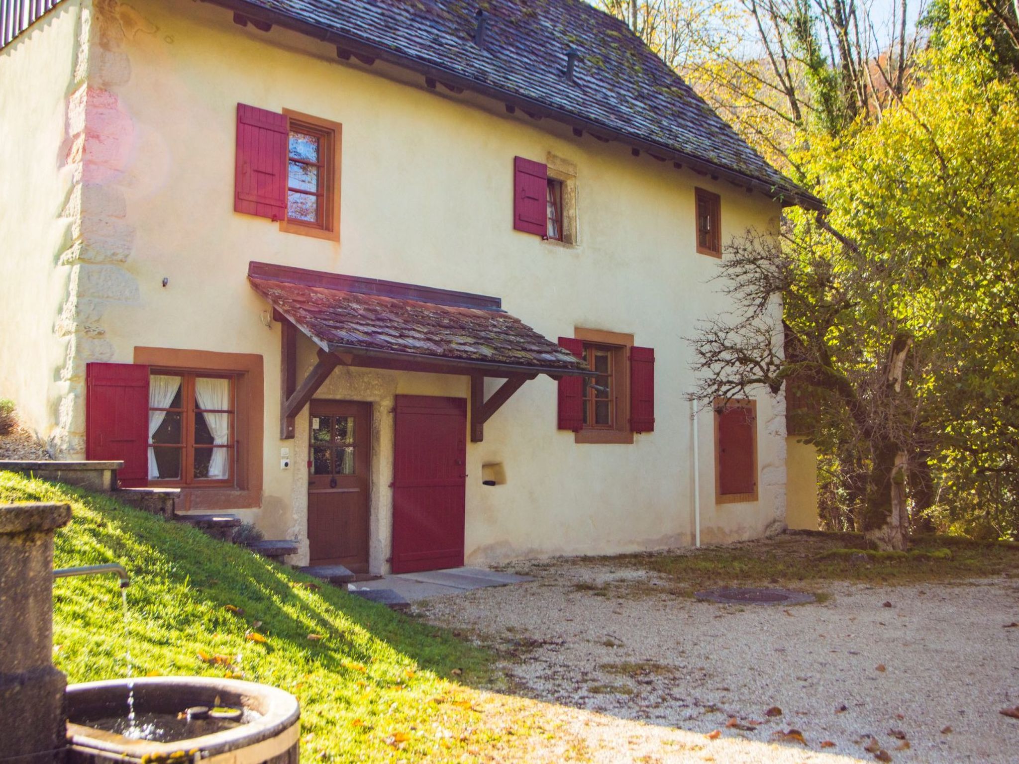 A two-story building with a sloped roof, a front porch, and a gravel driveway.
