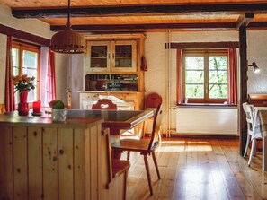 Un interior de fusta amb zona de cuina, taula de menjador i cadires.