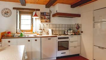 A kitchen with white cabinets, a stove, a sink, and a window.