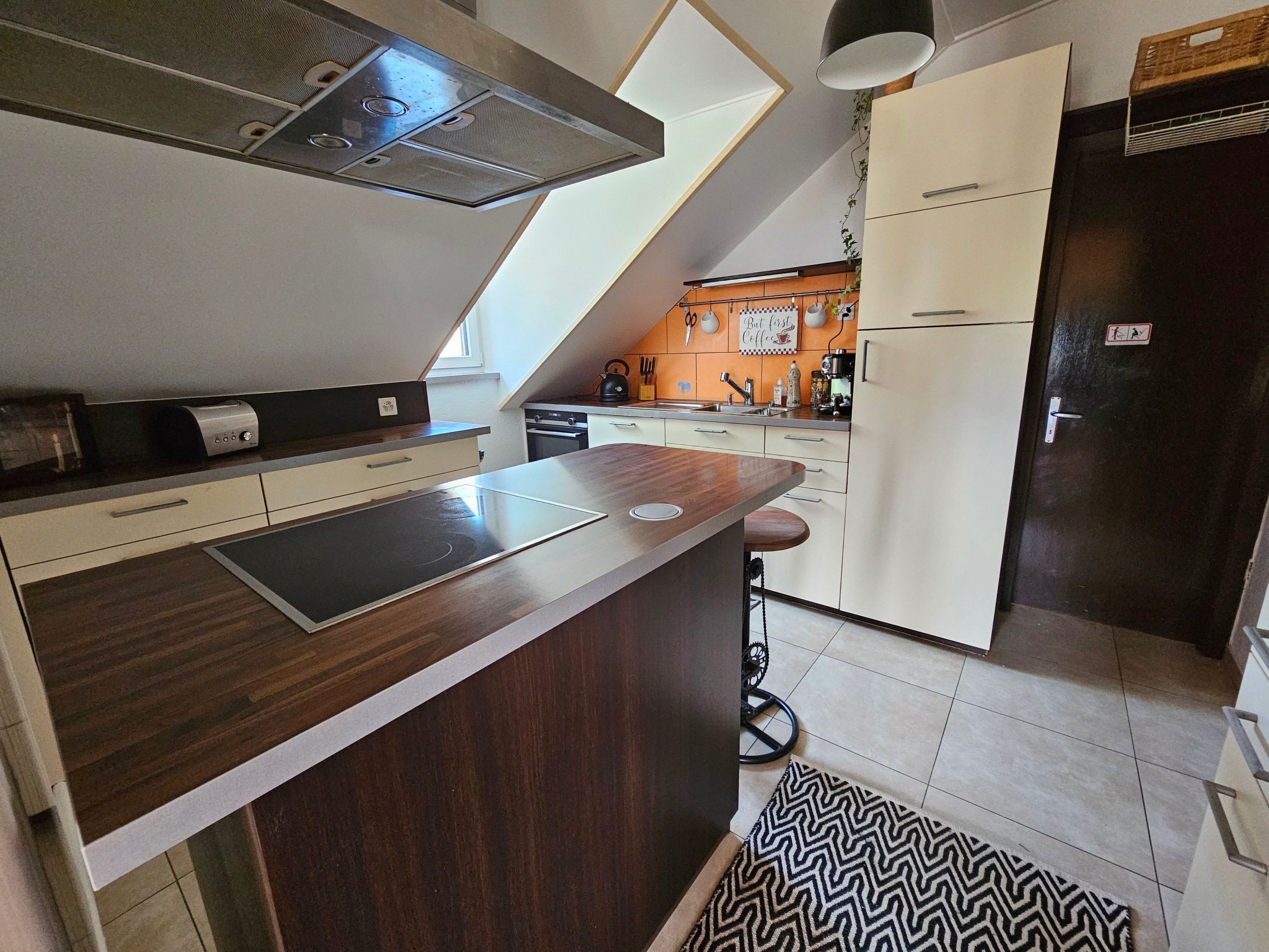 A modern kitchen with a central island, a built-in oven, and a refrigerator.