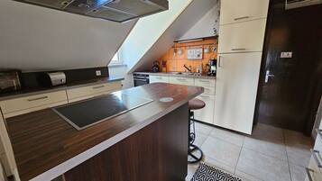 A modern kitchen with a central island, a built-in oven, and a refrigerator.