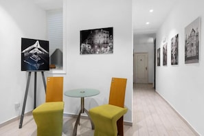 A hallway with a small table and two chairs, a painting on the wall, and a door at the end. - Myla's rooms (Palermo)