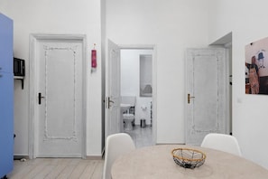 A room with a dining table, chairs, and a white door leading to a bathroom. - Myla's rooms (Palermo)