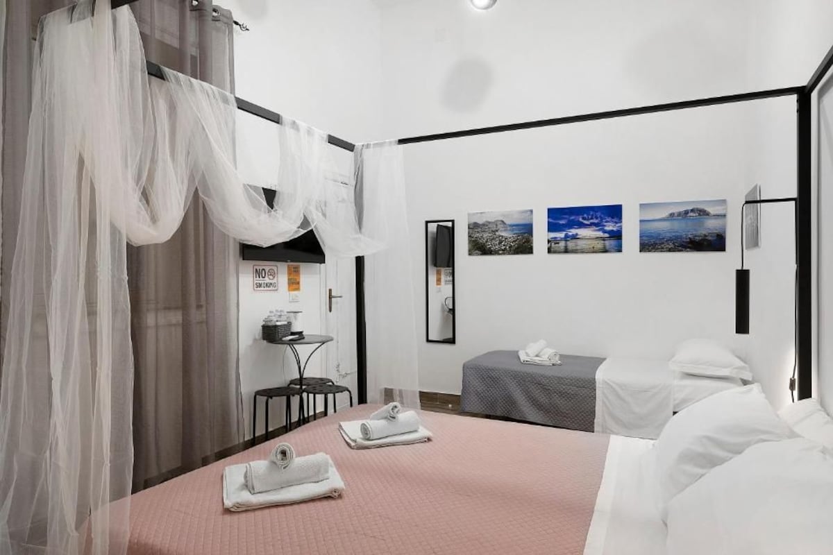 A hotel room with a bed, two bedside tables, a desk, and a chair. There are three framed pictures on the wall.