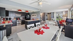 A modern kitchen with a dining area, a ceiling fan, and a view of the outdoors. - Stay Where The Rockets Launch & The Waves Roll In! (Satellite Beach)