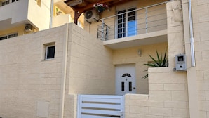Ein mehrstöckiges Gebäude mit Balkon, einer weißen Tür und einem kleinen Fenster.