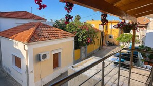 Ein Balkon mit Metallgeländer, einem Ziegeldach und Blumentöpfen.