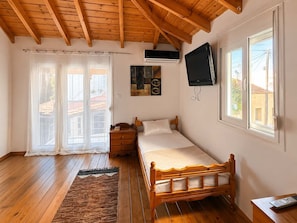 A bedroom with a wooden bed, a television, an air conditioning unit, and a window with a view of buildings. - Bella Casa Lydia -cozy Stay in the Heart of Rhodes (Rhodes)