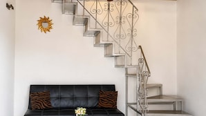 Ein Wohnzimmer mit einer schwarzen Ledersofa, einem Holztisch und einer Metalltreppe mit einer dekorativen Leuchte.