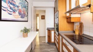 A modern kitchen with wooden cabinets, a built-in oven, and a stainless steel stovetop. - C204-058 UHC ANTINEA I APARTAMENTS (Cambrils)